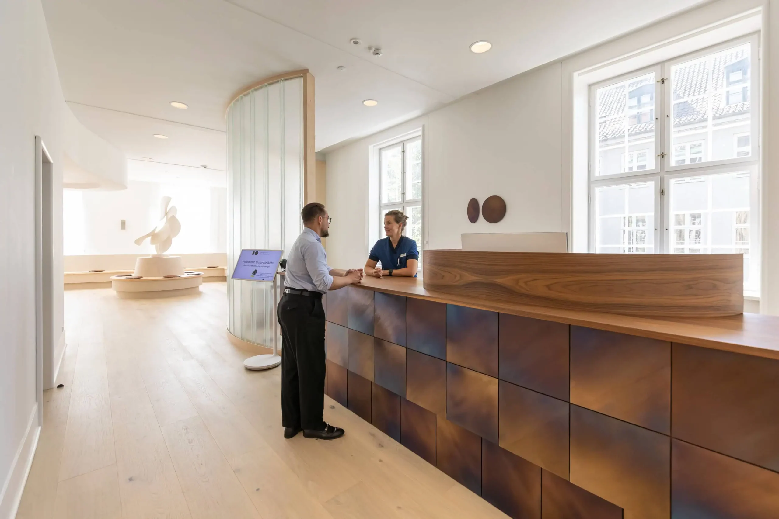 Øjenlæge København: Patient taler med sekretær ved receptionen på øjenklinik