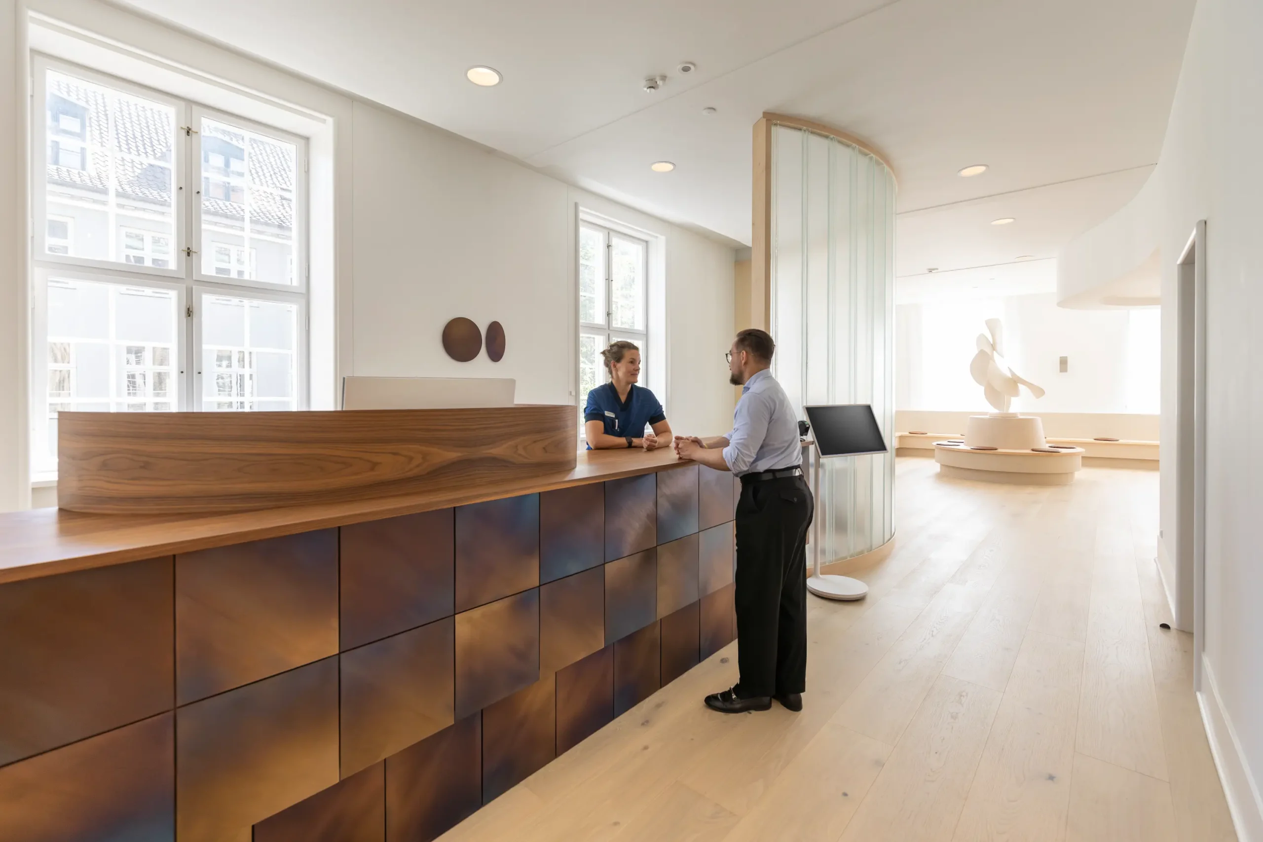 Patient taler med sekretær ved receptionen hos Copenhagen Eye Institute, øjenlæge i København